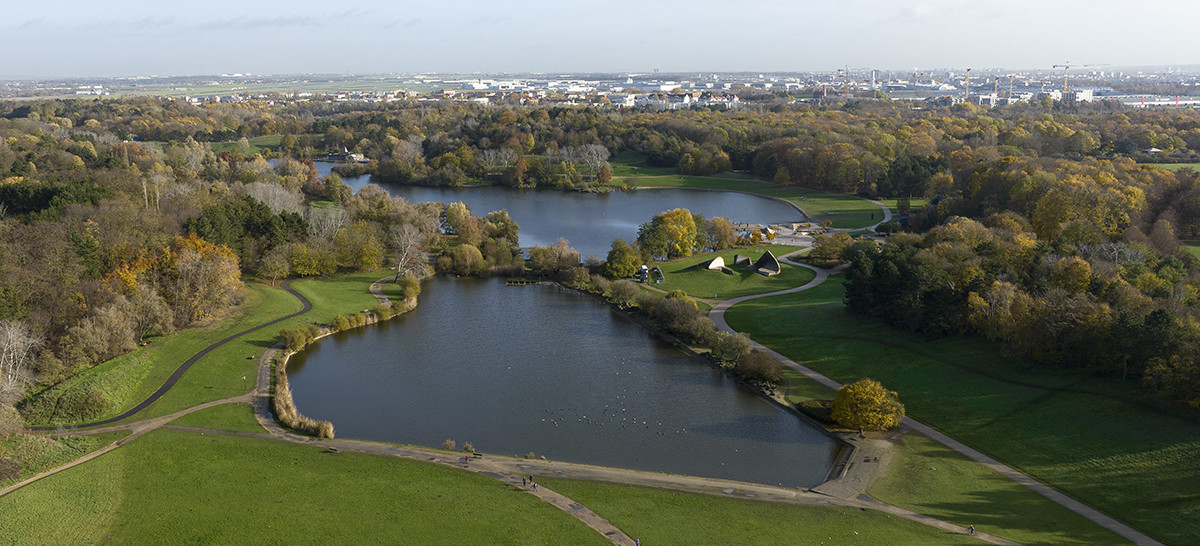 Visuel montrant des lacs et un immense parc avec la ville qui apparaît en fond